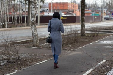 Paltolu kız kapı boyunca yürüyor. Dışarısı serin. Arkadaki adam. Yoldaki bir kadın.