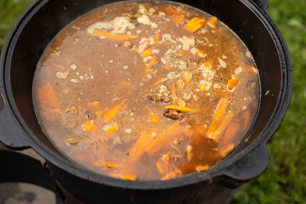 Soup in a pot. Food outside. Cooking soup on an open fire. National dish. Fatty food.