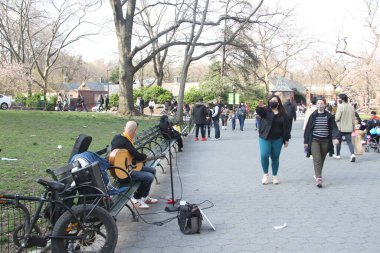 İnsanlar Paskalyayı Central Park 'ta kutluyor. 4 Nisan 2021, New York, ABD: İnsanlar sevdikleriyle Central Park 'ta Paskalya kutlaması yaparken, piknik yaparken, güneşli havanın keyfini çıkarırken, bisiklete binerken, patene binerken, scooterlara binerken, 