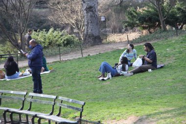 İnsanlar Paskalyayı Central Park 'ta kutluyor. 4 Nisan 2021, New York, ABD: İnsanlar sevdikleriyle Central Park 'ta Paskalya kutlaması yaparken, piknik yaparken, güneşli havanın keyfini çıkarırken, bisiklete binerken, patene binerken, scooterlara binerken, 