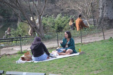 İnsanlar Paskalyayı Central Park 'ta kutluyor. 4 Nisan 2021, New York, ABD: İnsanlar sevdikleriyle Central Park 'ta Paskalya kutlaması yaparken, piknik yaparken, güneşli havanın keyfini çıkarırken, bisiklete binerken, patene binerken, scooterlara binerken, 