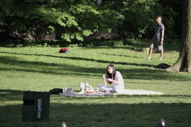 Covid-19 'un ortasında kalabalık bir Central Park. 15 Mayıs 2021, New York, ABD: Bu güneşli cumartesi Central Park 'ta COVID-19' un ortasında ağır bir hareket yaşandı. İnsanlar Central Park çimlerinde eğleniyor, piknik yapıyor, spor yapıyor ve müzik yapıyorlar. Çoğu 