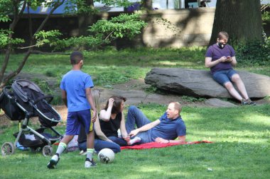 Covid-19 'un ortasında kalabalık bir Central Park. 15 Mayıs 2021, New York, ABD: Bu güneşli cumartesi Central Park 'ta COVID-19' un ortasında ağır bir hareket yaşandı. İnsanlar Central Park çimlerinde eğleniyor, piknik yapıyor, spor yapıyor ve müzik yapıyorlar. Çoğu 