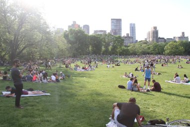 Covid-19 'un ortasında kalabalık bir Central Park. 15 Mayıs 2021, New York, ABD: Bu güneşli cumartesi Central Park 'ta COVID-19' un ortasında ağır bir hareket yaşandı. İnsanlar Central Park çimlerinde eğleniyor, piknik yapıyor, spor yapıyor ve müzik yapıyorlar. Çoğu 