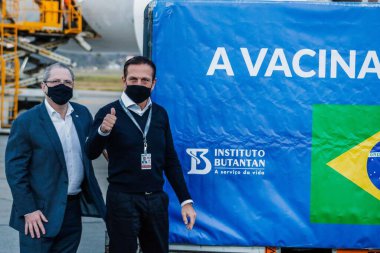 Sao Paulo. 25 Mayıs 2021 - Korona aşısı üretimi için girişlerin gelişi. Brezilya: Sao Paulo Valisi Joao Doria ve Sağlık Bakanı Jean Gorinchteyn, 3.000 litre Active Pharmace 'ın inişine eşlik ediyorlar  