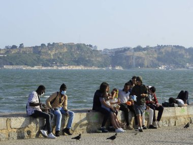 İnsanlar Lizbon 'daki Cais do Sodre' de günbatımının tadını çıkarıyorlar. 31 Mayıs 2021, Lizbon, Portekiz: İnsanlar Pazartesi günü Lizbon 'un kartpostallarından biri olan Tejo Nehri' nin kıyısındaki Cais do Sodre 'de gün batımının keyfini çıkarıyorlar.)