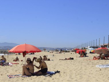 (INT) Banyo yapanlar, Portekiz 'in Costa da Caparica sahilinde güneşli bir günün tadını çıkarıyorlar. 8 Haziran 2021, Almada, Portekiz: Portekiz kıyısındaki Costa da Caparica plajında 8 Haziran Salı günü Avrupa kıtasındaki havuz temizleyicilerinin hareketi. Fotoğraf: Edson de Souza / Th