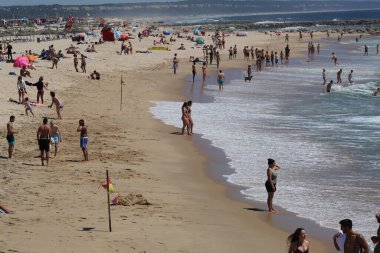 (INT) Banyo yapanlar, Portekiz 'in Costa da Caparica sahilinde güneşli bir günün tadını çıkarıyorlar. 8 Haziran 2021, Almada, Portekiz: Portekiz kıyısındaki Costa da Caparica plajında 8 Haziran Salı günü Avrupa kıtasındaki havuz temizleyicilerinin hareketi. Fotoğraf: Edson de Souza / Th