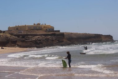 Bathers and sports enthusiasts on Guincho beach, in Cascais. June 30, 2021, Cascais, Portugal: Surfers, windsurfers and kite surfers enjoy winds and pleasant climate at Guincho beach, in district of Cascais, in metropolitan region of Lisbon
