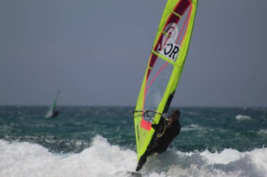 Bathers and sports enthusiasts on Guincho beach, in Cascais. June 30, 2021, Cascais, Portugal: Surfers, windsurfers and kite surfers enjoy winds and pleasant climate at Guincho beach, in district of Cascais, in metropolitan region of Lisbon