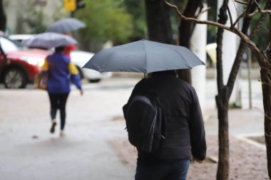 Yayalar kendilerini Sao Paulo 'da yağış ve soğuktan korur. 28 Temmuz 2021, Sao Paulo, Brezilya: Yoğun bir kutup hava kütlesiyle bağlantılı olarak, yeni bir soğuk hava cephesinin ilerlemesi Güney 'deki sıcaklıkları azaltmalı