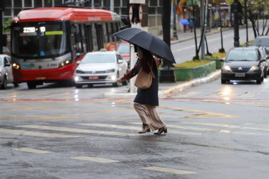 Yayalar kendilerini Sao Paulo 'da yağış ve soğuktan korur. 28 Temmuz 2021, Sao Paulo, Brezilya: Yoğun bir kutup hava kütlesiyle bağlantılı olarak, yeni bir soğuk hava cephesinin ilerlemesi Güney 'deki sıcaklıkları azaltmalı
