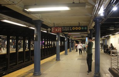 (New York Metrosu geri döndü ama biraz gecikmeyle. 2 Eylül 2021, New York, ABD: Bazı yolcular, kısa süreli tren seferlerine yol açan sağanak yağış nedeniyle perşembe günü New York 'ta trenlere binmekte hala sorun yaşıyorlar