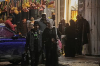 Soğuk Cephe Strip 'i vururken Gazze' deki Aileler Fırtınalı Caddelerde Yürüyor. 11-25 Aralık 2025 Gazze, Filistin: Şiddetli yağmur ve Gazze Şeridi boyunca esen şiddetli rüzgarların ortasında, aileler sokaklarda yürürken görüldü (hashem zimmo / the enews2)