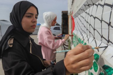 Gazze Limanı 'ndaki Yerdeğiştirme Kampları' nda Filistin Bayrağı Boyanmış. 8 Şubat 2026 Gazze, Filistin: Sanatçılar Farah Ajjour ve Şah Rajab, her ikisi de 20 'li yaşlarda, sıcak içecek satış büfesine Filistin bayrağının bir resmini yaptılar.