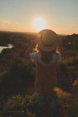 Gün batımında hasır şapkalı bir kız.