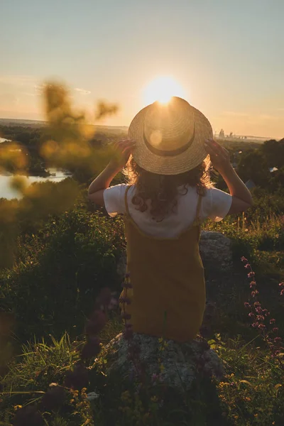 Gün batımında hasır şapkalı bir kız.