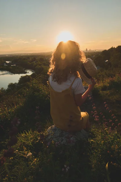 Gün batımında hasır şapkalı bir kız.