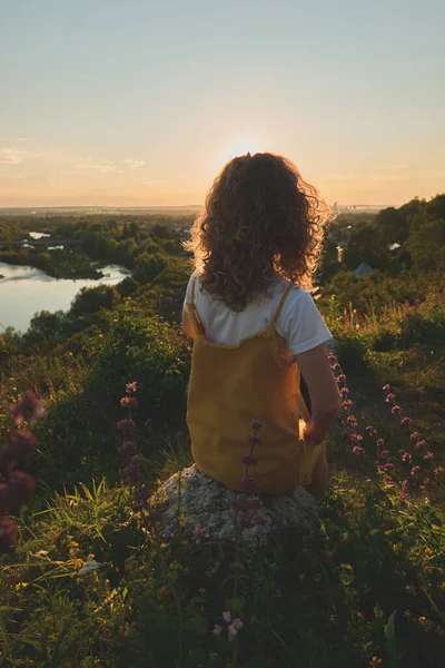 Gün batımında hasır şapkalı bir kız.