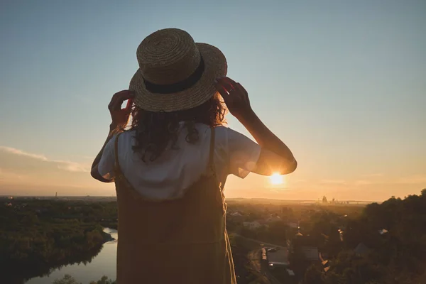 Gün batımında hasır şapkalı bir kız.