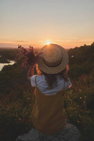 Gün batımında hasır şapkalı bir kız.