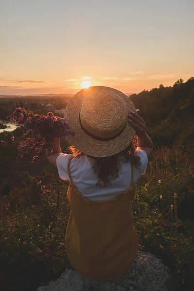 Gün batımında hasır şapkalı bir kız.