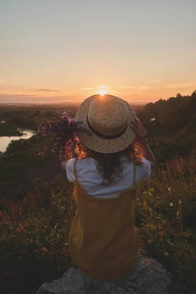 Gün batımında hasır şapkalı bir kız.