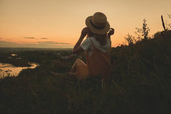 Gün batımında hasır şapkalı bir kız.