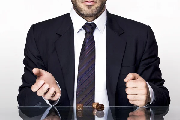 Geschäftsmann in Anzug und Krawatte zockt mit Holzwürfeln auf einem Glastisch — Stockbild Mann zockt — Stockfoto