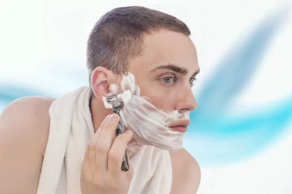 Mann som barberer seg i speilet – stockfoto
