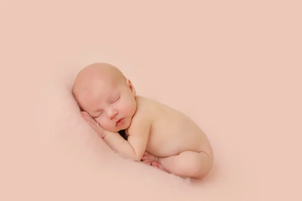 Newborn baby lying curled up on the belly and sleeps