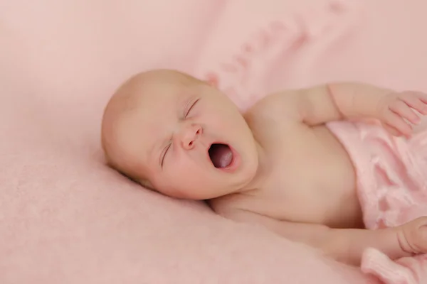 Bebé recién nacido durmiendo desnudo y bostezando en manta rosa —  Fotos de Stock