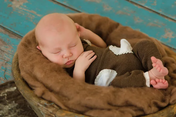 Νεογέννητο μωρό στον ύπνο σε ένα ξύλινο μπολ με καφέ τσόχα — Φωτογραφία Αρχείου