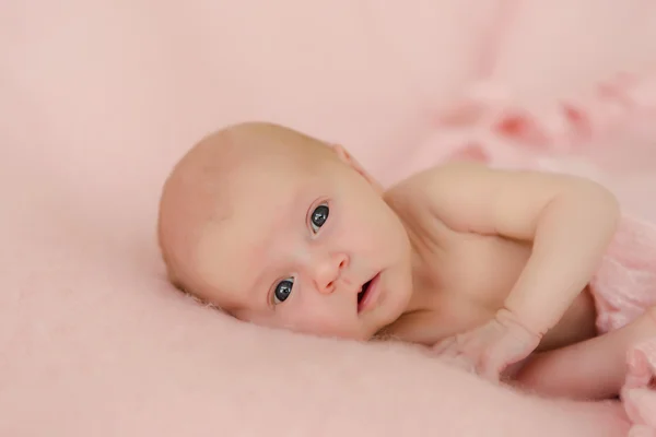 Новорожденная девочка широко раскрыла глаза на розовом одеяле — стоковое фото