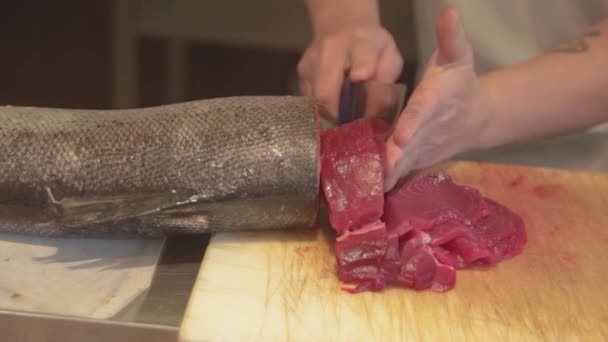 Homem a cortar filé de atum. Corte em pedaços de filé de atum em uma tábua de madeira — Vídeo de Stock