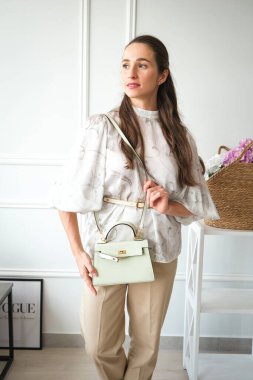 Açık yeşil deri bir çanta taşıyan bir kadının taze ve şık bir fotoğrafı. Mevsimlik bahar pazarlaması, kadınsı aksesuar kataloğu ve modaya uygun yaşam tarzı makaleleri için mükemmel..
