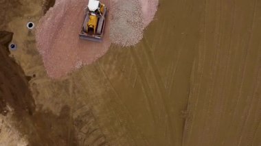 İnşaat alanında toprağı hareket ettiren bir buldozerin İHA görüntüsü.