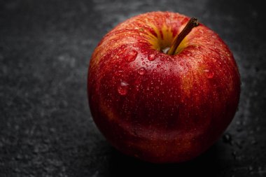 Sulu kırmızı elmalı, sulu, siyah bir masaya yakın su damlaları. 