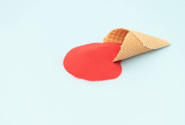 Pastel mavi arka planda koyu kırmızı kumlu dondurma külahı. Asgari yaratıcı estetik.