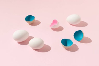 Beyaz yumurtalardan yapılmış yaratıcı Paskalya kompozisyonu ve parlak pembe arka planda mavi ve pembe yumurta kabukları. En az gıda sanatı konsepti.