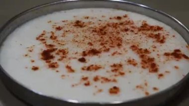 Khaman olarak da bilinen beyaz dhokla 'nın üzerine beyaz hamurdan yapılmış Gujrati tabağı ve üzerine kırmızı biberli masala dökülüyor. 