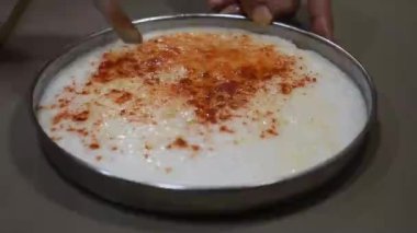 Khaman olarak da bilinen beyaz dhokla 'yı elleriyle simetrik kare şeklinde kesen Gujrati kabı, beyaz vurucudan yapılmıştır. 
