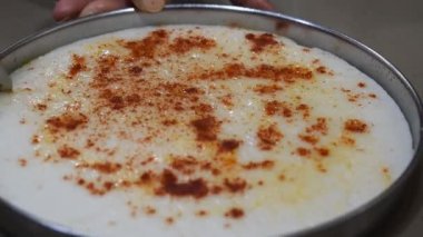 Elleriyle simetrik kare şeklinde Khaman olarak da bilinen beyaz dhokla 'yı kesen Gujrati kabı, beyaz hamurdan ve kırmızı serin masaladan yapılmıştır.