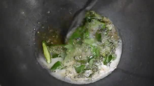 慢动作烹调食物炒咖喱叶 用油和绿色的辣椒和杰拉调味 近观极致 用勺子在器皿里调味 — 图库视频影像