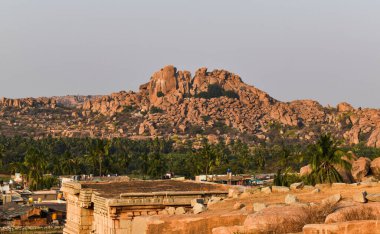 Hampi manzaralı kaya kesimi dağlar ve mavi gökyüzü ile hindistan cevizi ağacı. UNESCO Dünya Mirası Bölgesi Doğu-Orta Karnataka, Hindistan 'da yer almaktadır.