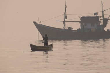 Geleneksel yelkenliyle denizde kürek çeken bir adam.