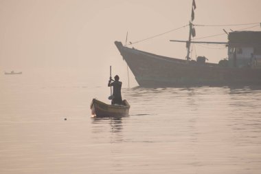 Adam sabah kürekle geleneksel yelkenliyle denizde yüzüyor.