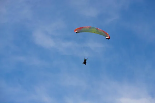 Paraşütçüler dağların üzerinden gökyüzünde süzülür.