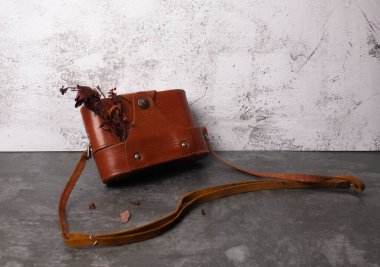 Deri bir çantada eski bir fotoğraf makinesi olan klasik bir kartpostal.