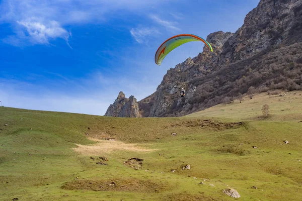 Paraşütçüler dağların üzerinden gökyüzünde süzülür.